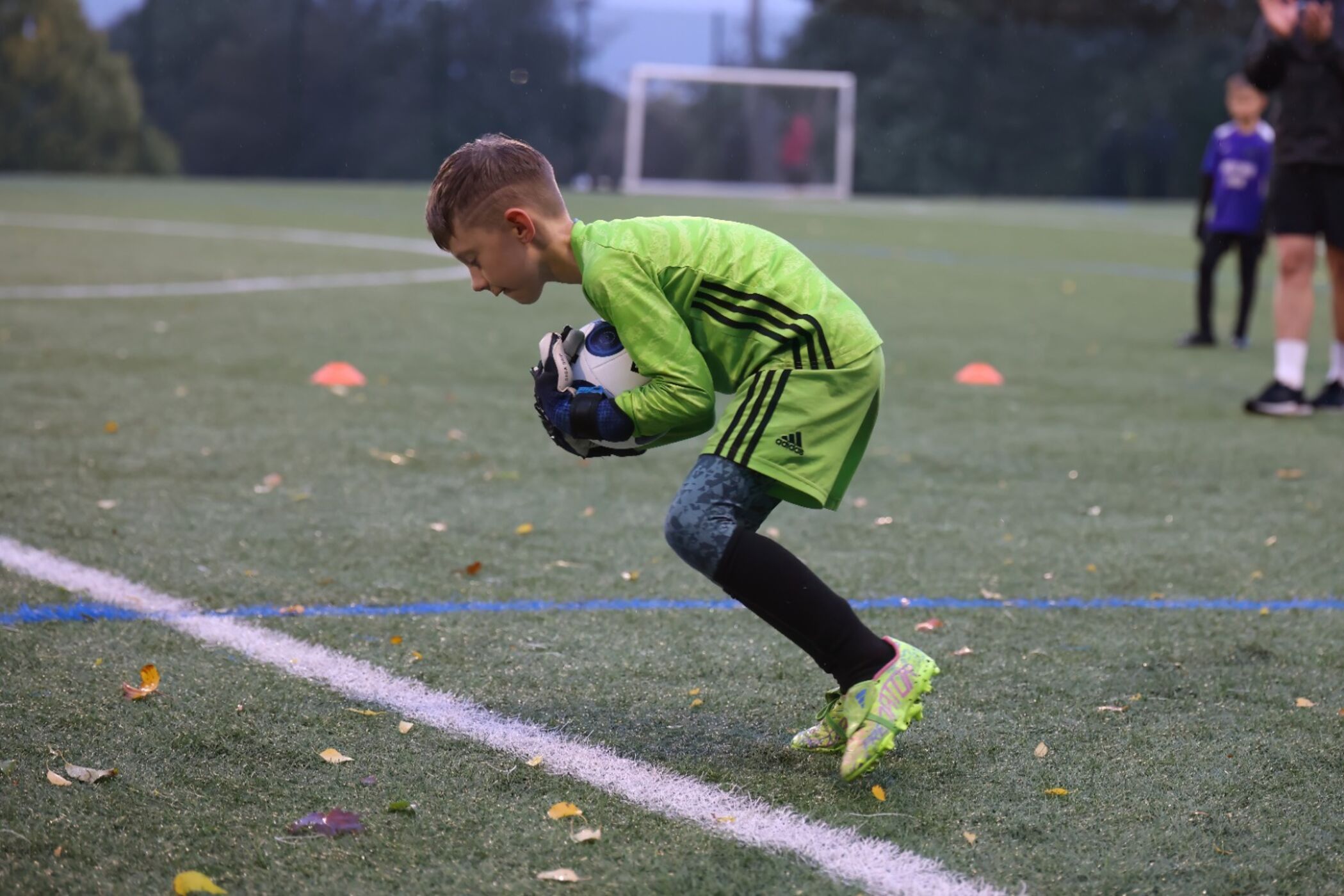 Young goalkeeper gathering the ball at training