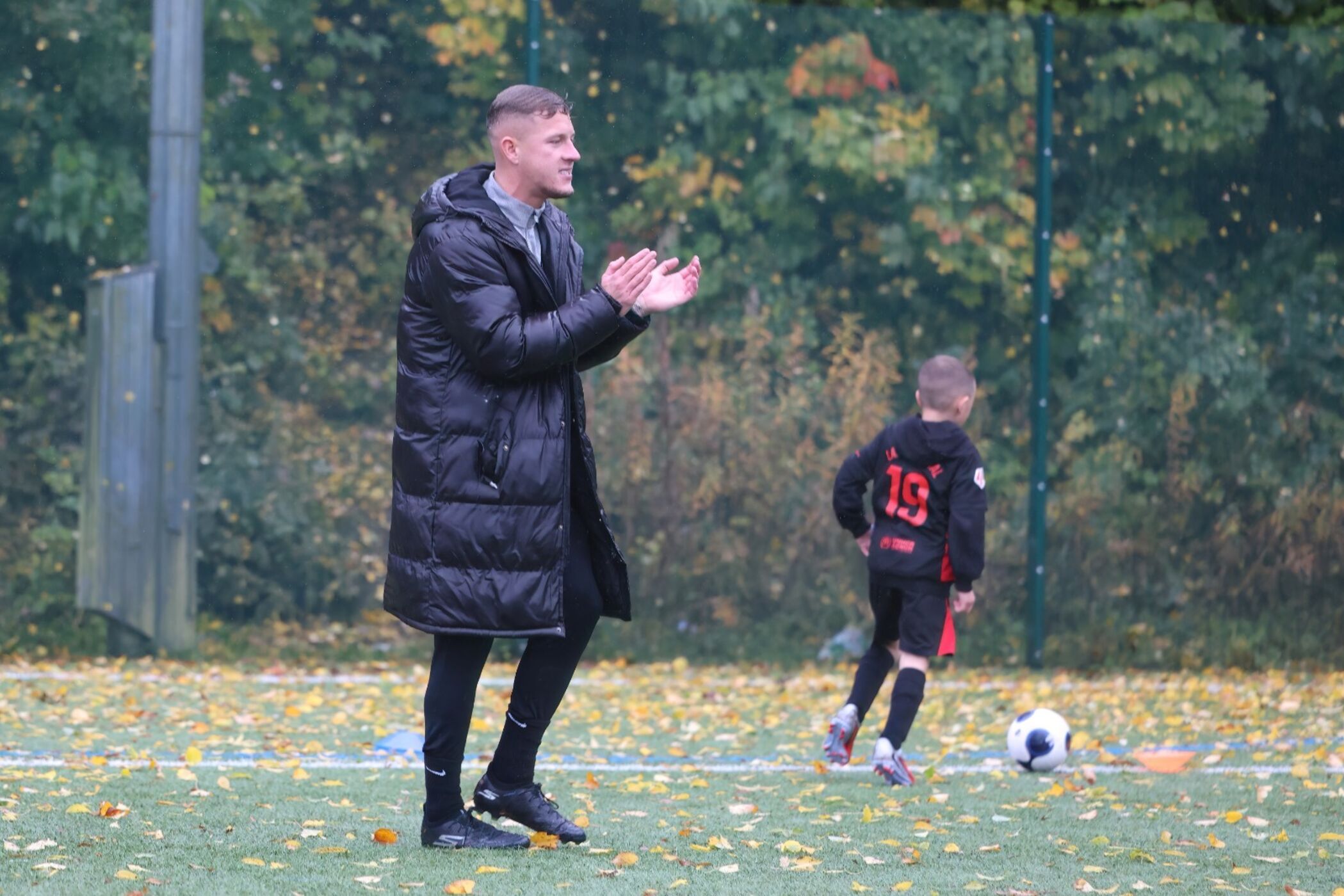 Coach applauding players during a wet-weather session